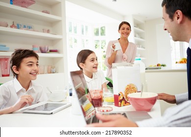 Family Using Digital Devices At Breakfast Table