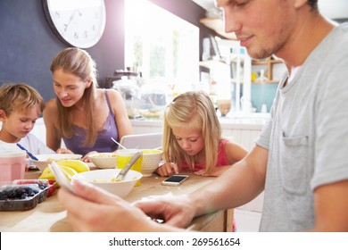 Family Using Digital Devices At Breakfast Table