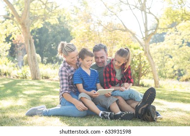 Family Using Digital Tablet In The Park On A Sunny Day