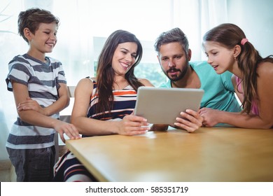 Family using digital tablet while sitting at table in home
