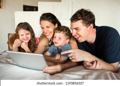 Family using a laptop in bed - Shutterstock ID 1193856337