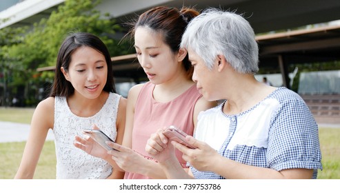 Family Using Mobile Phone Together At Outdoor Park 