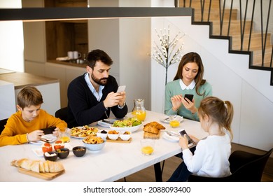 Family using mobile phones while having breakfast at dining table at the apartment - Powered by Shutterstock