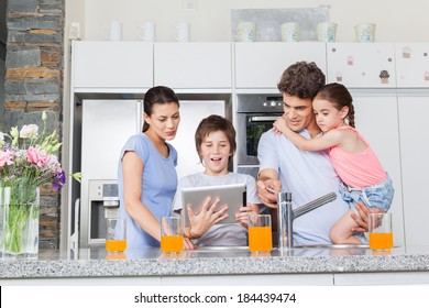 Family using a tablet pc in kitchen, parents with children happy smile, modern kitchen orange juice - Powered by Shutterstock