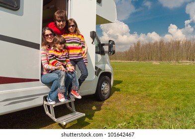 Family Vacation In Camping. Happy Active Parents With Kids Travel On Camper (RV). Family Having Fun Near Their Motorhome. Spring Vacation Trip With Children.