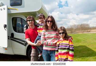 Family Vacation In Camping. Happy Active Parents With Kids Travel On Camper (RV). Family Having Fun Near Their Motorhome. Spring Vacation Trip With Children.