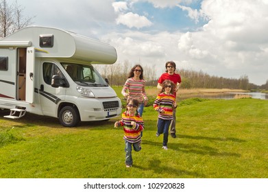 Family Vacation In Camping. Happy Active Parents With Kids Travel On Camper (RV). Family Having Fun Near Their Motorhome. Spring Vacation Trip With Children.