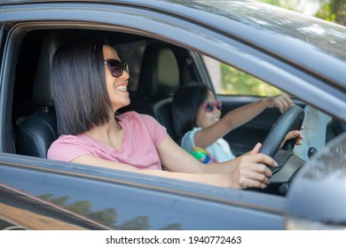 Family Vacation Holiday, Happy Family On A Road Trip In Their Car, Mom Driving Car While Her Daughter Sitting Beside, Mom And Daughter Are Traveling. Summer Ride By Automobile.