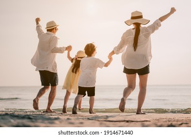 Family vacation holiday, Happy family running on the beach in the evening. Back view of a happy family on a tropical beach. Mother, father, children on the sea at sunset.