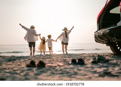 Family Vacation Holiday, Happy Family Running On The Beach In The Sunset. Back View Of A Happy Family On A Tropical Beach And A Car On The Side.