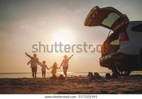 Family vacation holiday, Happy family running on\
the beach in the sunset. Back view of a happy family on a tropical\
beach and a car on the side.\
