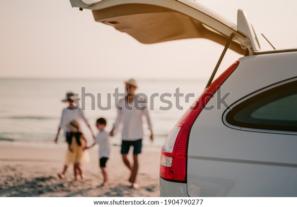Family
vacation holiday, Happy family running on the beach in the
sunset.Happy family is walking into the car.Back view of a happy
family on a tropical beach and a car on the
side.