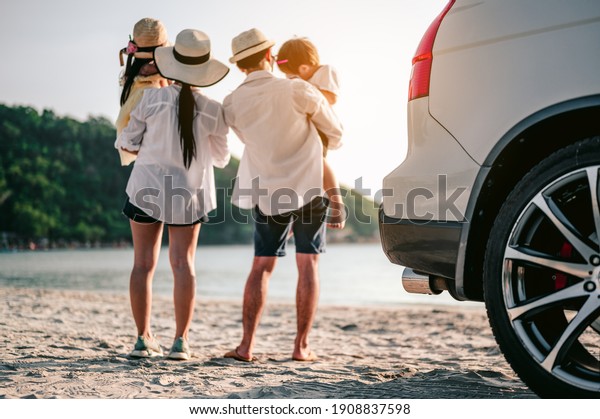 Family vacation holiday, Happy family\
running on the beach in the sunset.Parents were holding their\
children and watching the sunset behind the\
car.