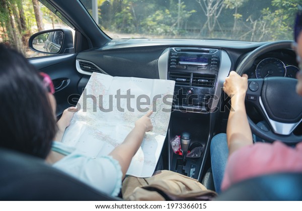 Family vacation holiday  looking on map,
happy family on a road trip in their car, mom driving car while her
daughter sitting beside, mom and daughter are traveling. summer
ride by automobile.