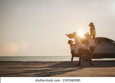 Family Vacation Holiday, Silhouette Of The Happy Family On The Evening Beach. Father And Mother Are Happily Carrying Their Son And Daughter On The Beach, Car And Bicycles In The Back.