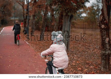 Family, vacation and people concept - mother and little daughter riding bicycles on the bike path in autumn rear view. traffic, city transport and people concept