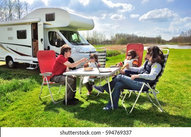 Family Vacation, RV (camper) Travel With Kids, Happy Parents With Children Sit At The Table In Camping On Holiday Trip In Motorhome
