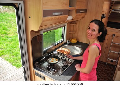 Family Vacation, RV Holiday Trip, Camping. Happy Smiling Woman Cooking In Camper. Motorhome Interior