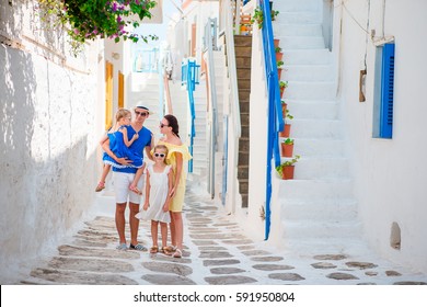 Family vacation in small european city. Parents and kids at street of greek traditional village on Mykonos Island