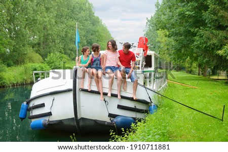 Family vacation, summer holiday travel on barge boat in canal, happy kids and parents having fun on river cruise trip in houseboat in France
