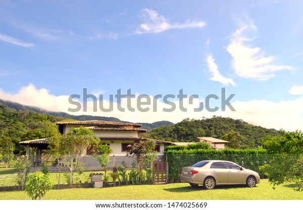 Family vacation travel , holiday trip car in\
sunny day. Big house and beige car. Beautiful Nature Brazil natural\
landscape.
