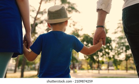 Family vacation, weekend. Happy parents and children walking in park. Happy family walks with a child on quiet street in summer at sunset. Dad, son, mom and hold hands on the sidewalk in city in sun. - Powered by Shutterstock