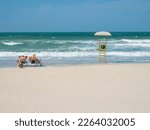 A family of vacationers on sun loungers sunbathing, big waves in the sea. al khan beach. UAE,Sharjah