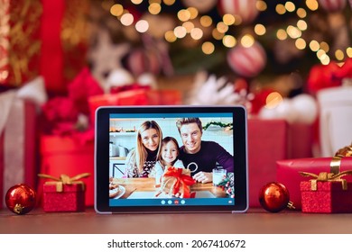 Family video call with kid presenting gift by remote chat digital tablet screen on Merry Christmas table holiday background. Xmas online virtual family party celebration, Happy New Year videocall. - Powered by Shutterstock