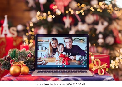 Family video call with kid presenting gift by remote chat laptop computer screen on Merry Christmas table holiday background. Xmas online virtual family party celebration, Happy New Year videocall. - Powered by Shutterstock