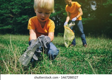 Family Of Volunteers With Children Collecting Garbage In Park. Save Environment Concept. Little Boy And His Father Cleaning Up The Forest. 