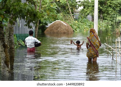 A Family  Wade Through A Flooded Road  To Residence, At Kalgachia Of Barpeta District Of Assam, India On July 12, 2019.