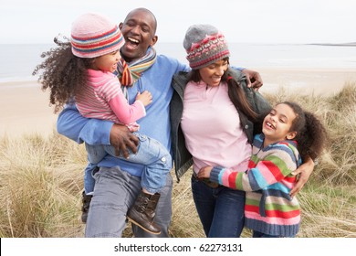 Family Walking Along Dunes On Winter Beach