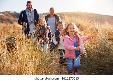 Family Walking Along Path Through Sand Dunes Together