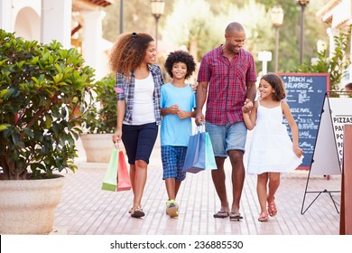 Family Walking Along Street With Shopping Bags