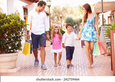 Family Walking Along Street With Shopping Bags