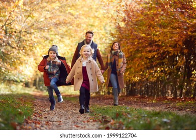 Family Walking Along Track In Autumn Countryside With Children Running Ahead