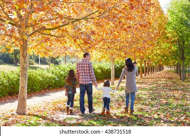 Family Walking In An Autumn Park With Fallen Fall Leaves