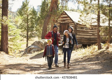 Family Walking Away From A Log Cabin In A Forest