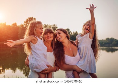 Family walking by summer river at sunset. Mother and grandmother holding kids and laughing. Three denerations - Shutterstock ID 1467870410