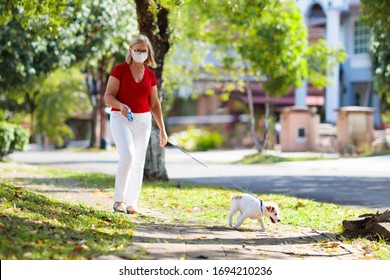 Family Walking Dog During Virus Outbreak. Woman And Child Wearing Face Mask In Coronavirus Lockdown And Quarantine. Home Animal And Pet. Mother And Child With Puppy In Pandemic Or Air Pollution.