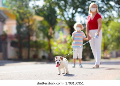 Family Walking Dog During Virus Outbreak. Woman And Child Wearing Face Mask In Coronavirus Lockdown And Quarantine. Home Animal And Pet. Mother And Child With Puppy In Pandemic Or Air Pollution.