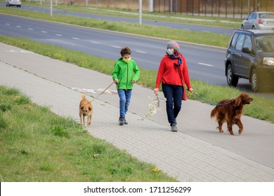 Family Walking Dog During Virus Outbreak. Mother And Son In Masks Walking The Dog Outside The House During Covid-19. Corona Virus Concept