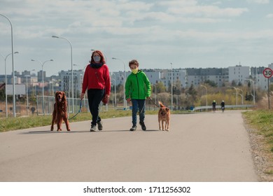 Family Walking Dog During Virus Outbreak. Mother And Son In Masks Walking The Dog Outside The House During Covid-19. Corona Virus Concept