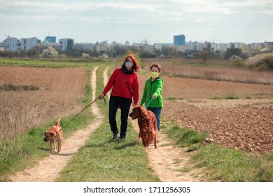 Family Walking Dog During Virus Outbreak. Mother And Son In Masks Walking The Dog Outside The House During Covid-19. Corona Virus Concept