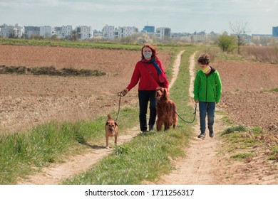 Family Walking Dog During Virus Outbreak. Mother And Son In Masks Walking The Dog Outside The House During Covid-19. Corona Virus Concept