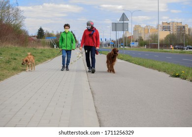 Family Walking Dog During Virus Outbreak. Mother And Son In Masks Walking The Dog Outside The House During Covid-19. Corona Virus Concept