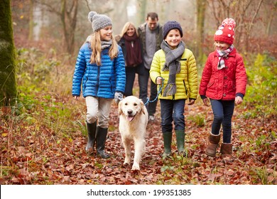 Family Walking Dog Through Winter Woodland