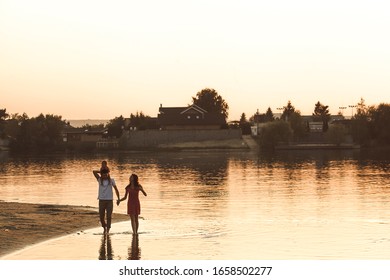 Family walking down the river near the water. Family silhuetts on sunset. Happy family on the lake.