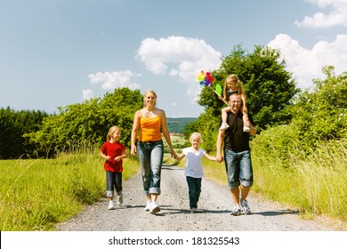 Family Walking Down A Rural Path On A Bright Summer Day.