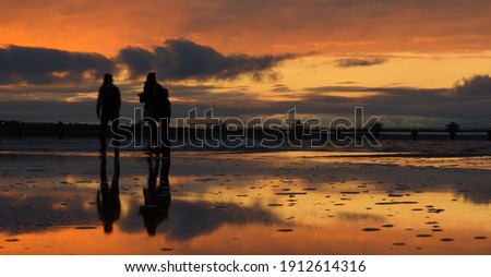 Międzyzdroje, a family walking in the evening on the shores of the Baltic Sea. Moved figures reflected in the water surface.